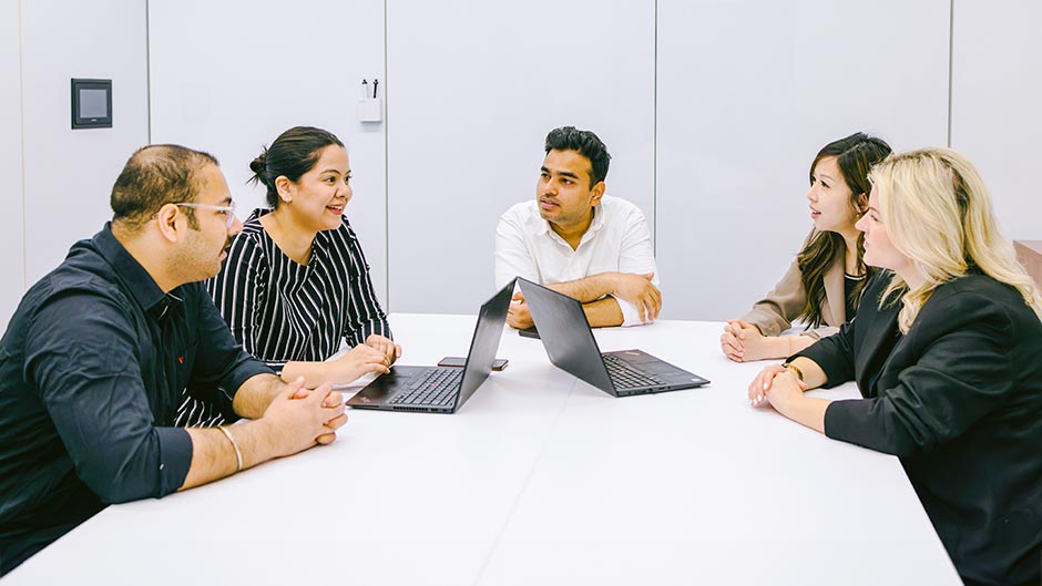 a group of diverse people working together around a table.