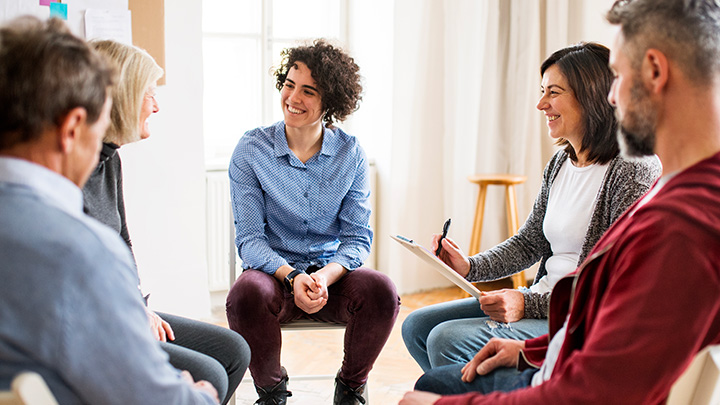 A group of people sitting in a circle conversing with one another.